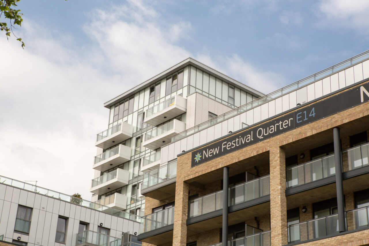 Moderne Wohngebäude im New Festival Quarter mit einer Kombination aus hellen Keramikpaneelen und Backsteinfassaden, großen Fenstern und Balkonen, die eine abwechslungsreiche und strukturierte Optik bieten