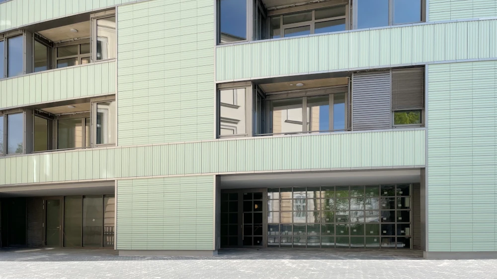 Tonality Keramikfassade am elliptischen Gebäude in Ljubljana, Seitenansicht, die das moderne und elegante Design der Fassadenplatten zeigt.