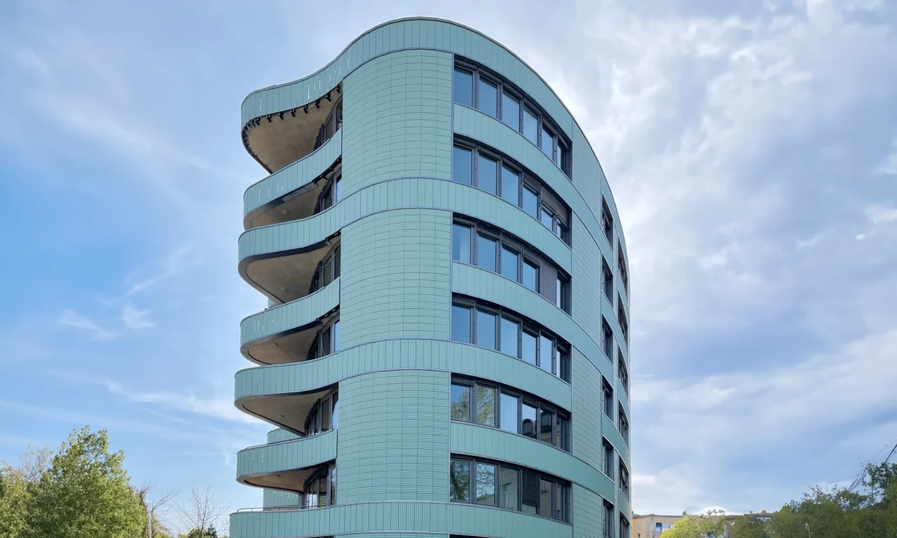 Tonality Referenzgebäude in Ljubljana mit elliptischer Form, Frontansicht, die die moderne Architektur und das innovative Design der Keramikfassade zeigt.