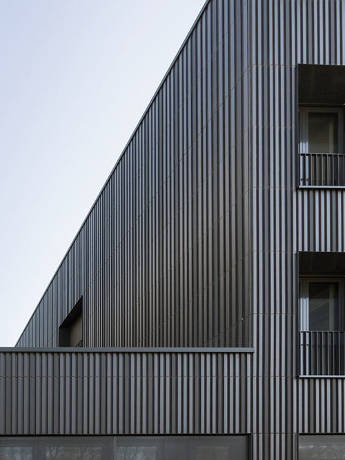 Keramikfassade eines modernen Gebäudes mit einer vertikalen, dunklen Keramikfassade.